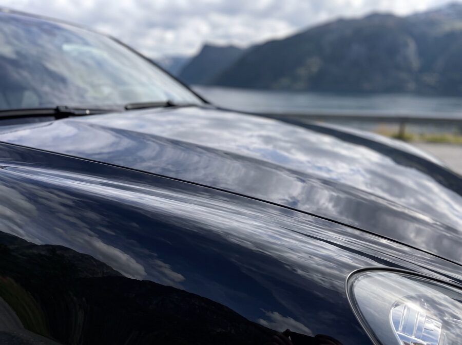 Porsche Cayenne sort etter detailing — speilblank med fjordrefleksjon