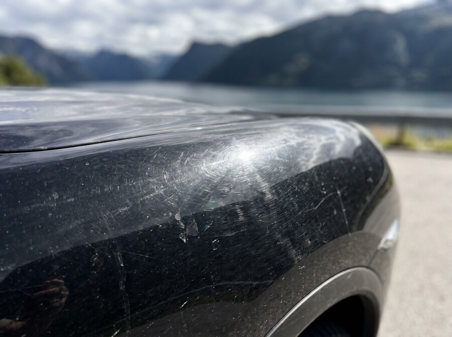 Porsche Cayenne sort før detailing — svirlmerker under rakende lys